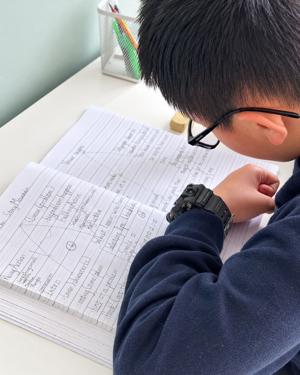 A pupil planning a story using a story mountain in his notebook